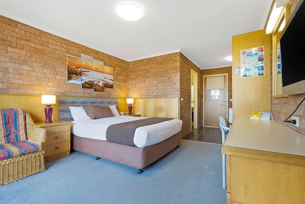 Standard Queen room with comfortable queen bed and feature brick wall